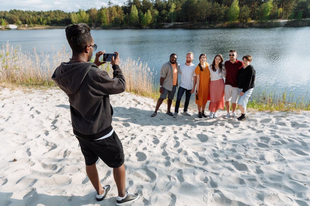 Friends posing by the lake, smiling for a photo together on a sunny day.
